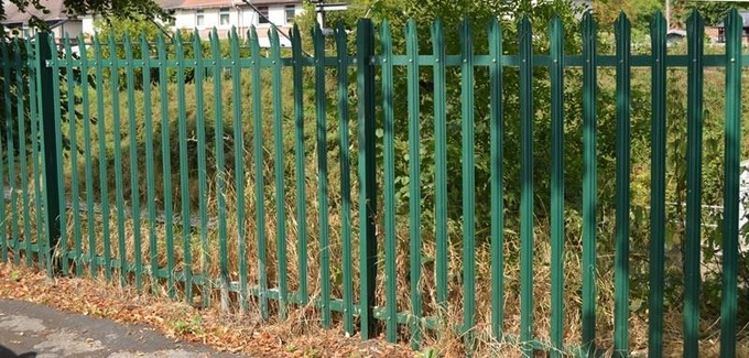 Green palisade fence is installed on the outside of houses and weeds, with pales being W-section and triple point head.