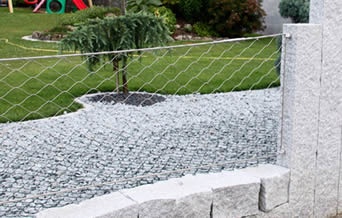 Stainless steel garden fencing mounted to stone base and columns are designed to protect your prized garden plants.