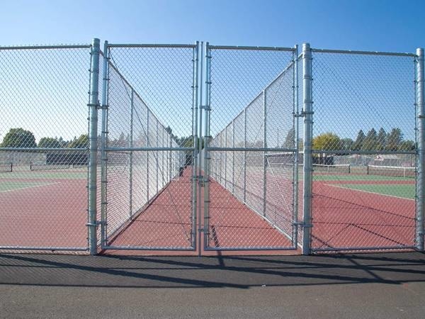 Two sports fields surrounded and separated by galvanized chain link fence.