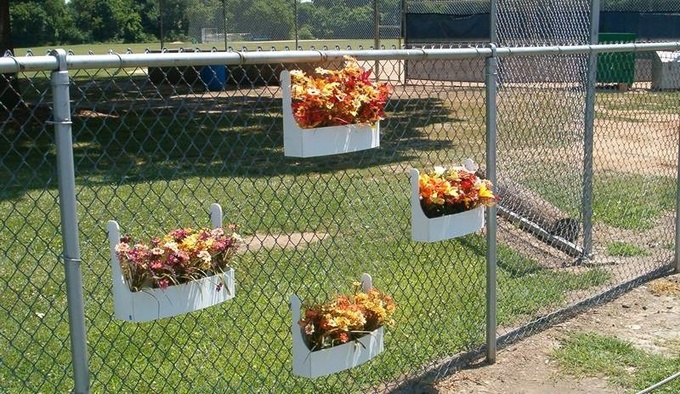 Flowers decorating galvanized chain link fence.