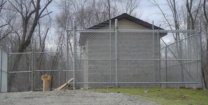 Galvanized high security chain link fence with cantilever gate and barbed wire.